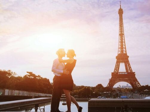 Couple kissing in front of the Eiffel Tower at sunset